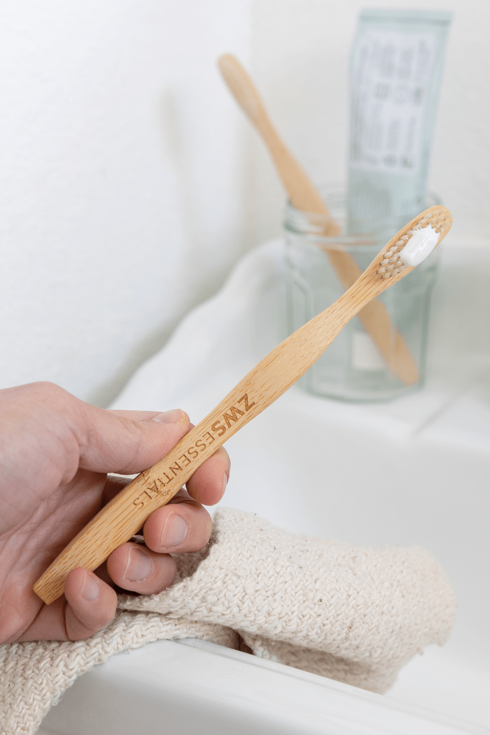 model holding bamboo toothbrush by sink model holding bamboo toothbrush by sink